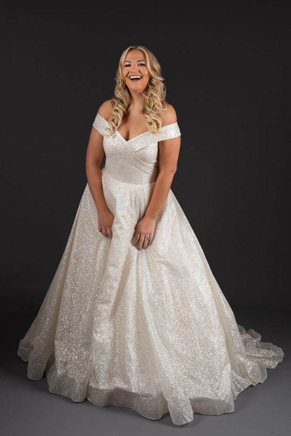 Model standing and laughing wearing Alice Bridal Dress stocked by Roberta's Bridal, Burslem